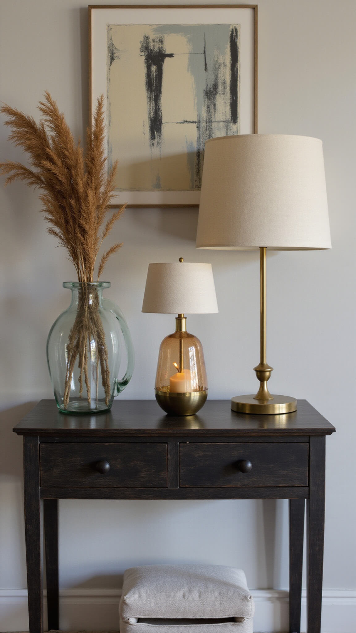 Compact 6x8ft Japandi entryway with blackened ash console, petite brass-accented table lamp, abstract art, and dried botanicals in morning light.