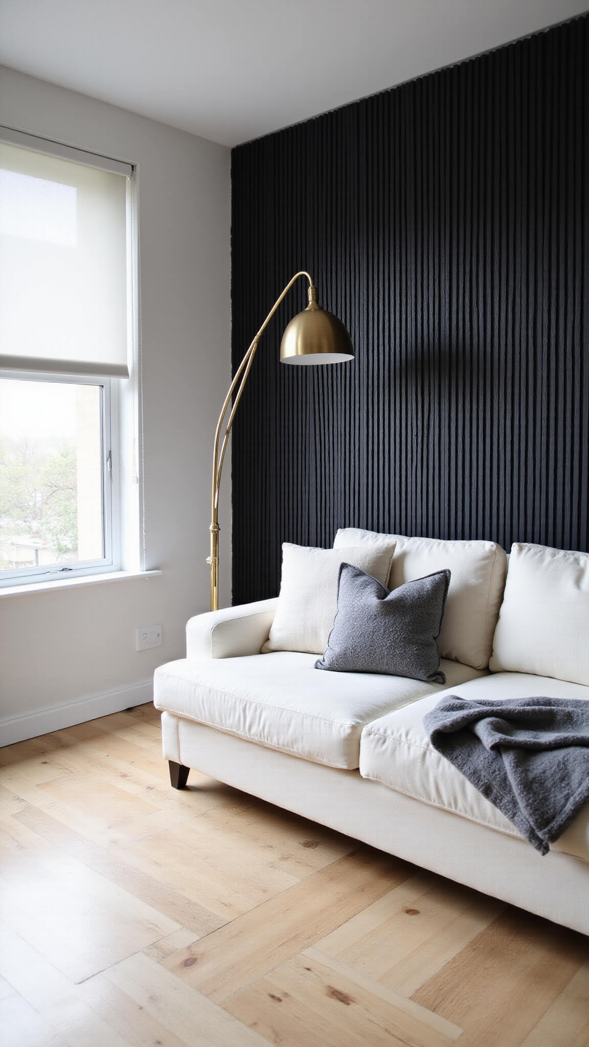 Scandinavian minimalist den with black vertical slat accent wall, white linen sectional, brass floor lamp, and light oak flooring in natural light.