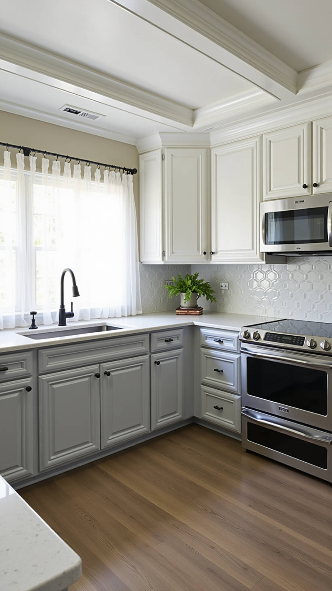 Transitional kitchen with white upper and gray lower cabinets, black stainless appliances, large island with prep sink, coffered ceiling, mixed metal finishes, and diffused afternoon light.