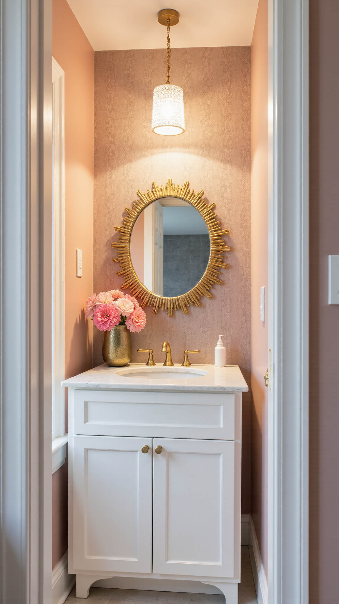 Blush-toned powder room with quartz vanity, gold sunburst mirror, crystal chandelier, and metallic grasscloth accent wall.