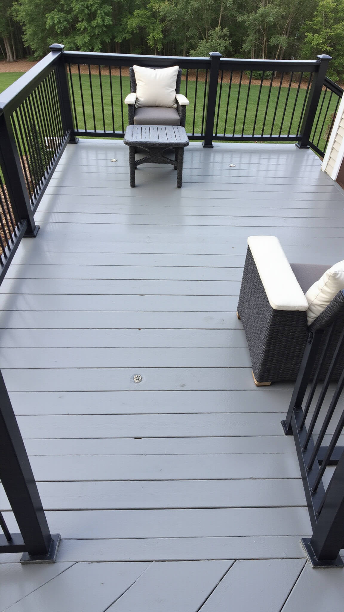 Minimalist 30x20ft deck with silver-grey composite decking, black aluminum railings, charcoal and white furniture, and recessed lighting, viewed from above at noon.