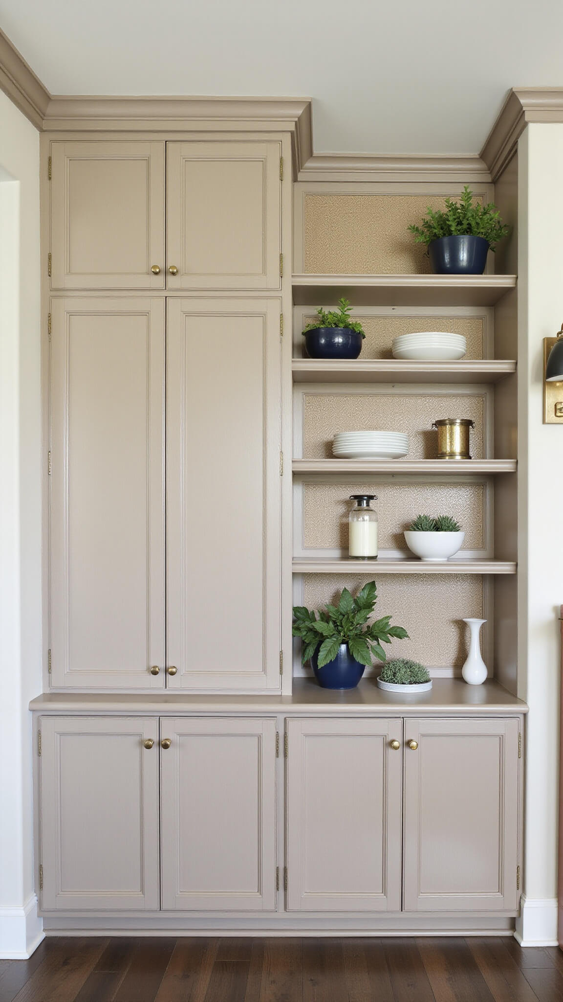 Transitional living room in morning light with Shaker-style built-ins, grasscloth-backed shelves, warm greige cabinets, navy accents, and aged brass fixtures.