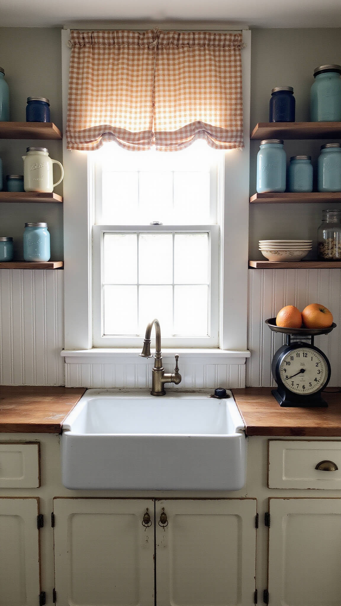 Cozy vintage kitchen corner with farmhouse sink under gingham-curtained window, aged brass faucet, white beadboard backsplash, open shelves of mason jars and enamelware, distressed wooden countertops, vintage scale with produce, bathed in soft morning light.