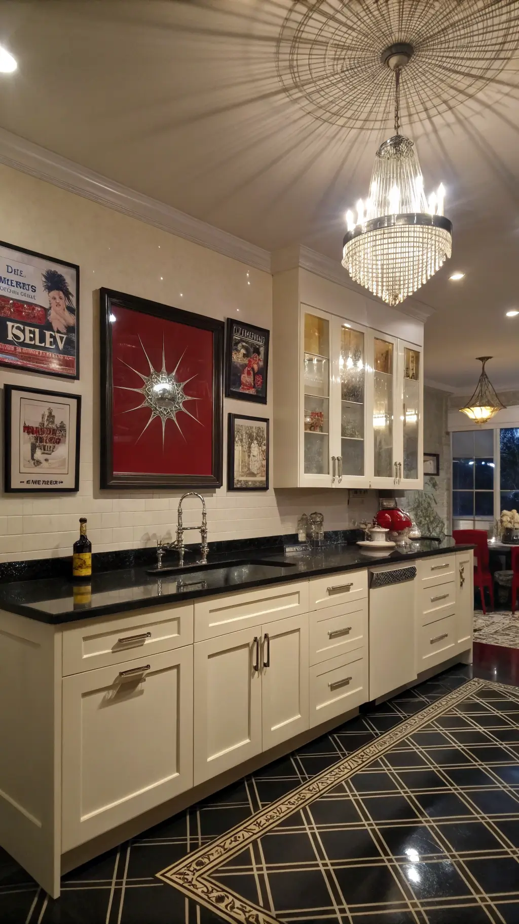 Art Deco kitchen at dusk with black granite counters, ivory cabinets, starburst chandelier, red accent wall, and geometric black-and-gold floor tiles.