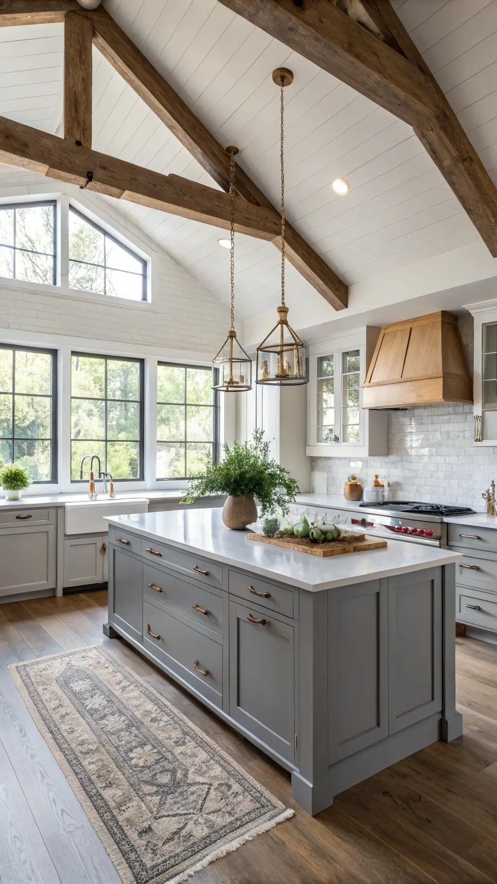 Modern farmhouse kitchen with gray shaker cabinets, white quartz countertops, exposed wooden beams, and sunlit windows showcasing a central island with vintage pendant lights.
