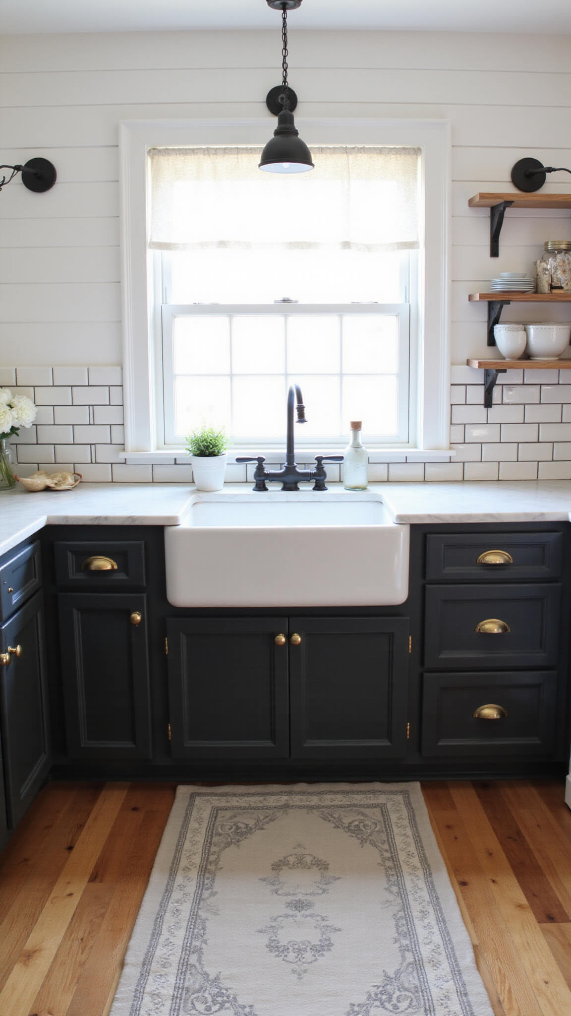 Bright farmhouse kitchen with black shaker cabinets, marble counters, apron-front sink under window, and morning sunlight filtering through lace café curtains.