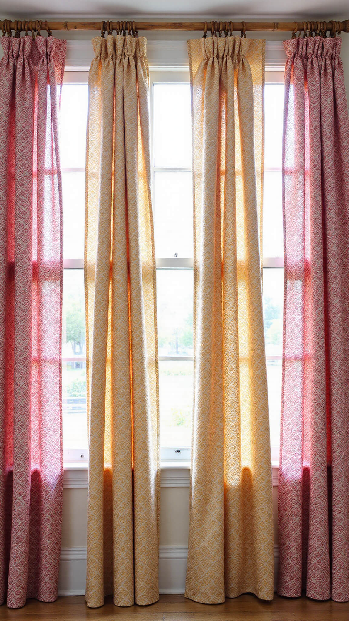 Eclectic dining room with fuchsia and saffron block-printed cotton drapes, striped sheers, and bamboo rods, bathed in morning light.